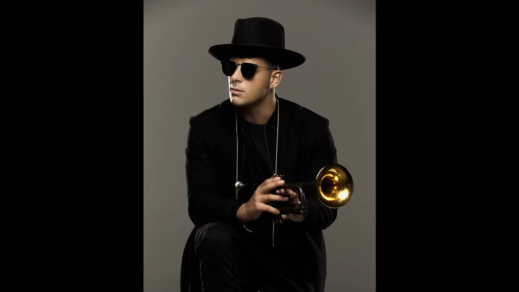 Timmy Trumpet sitting with his trumpet on his lap