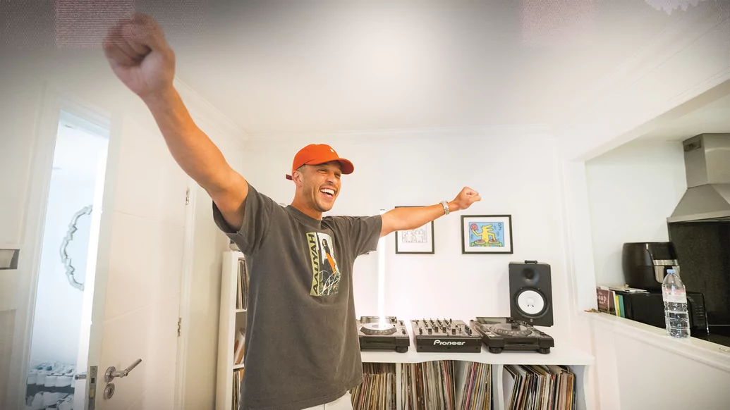 Photo of Melvo Baptiste smiling and holding out his arms in a white studio
