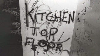 Black and white image of a graffiti'd wall that reads "Kitchen Top Floor"