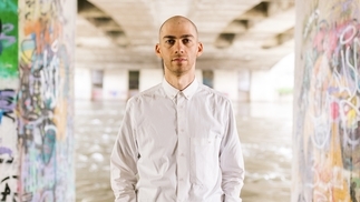 Photo of Alec Pace wearing a white shirt in a graffiti-covered underpass