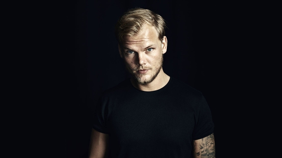 Photo of the late Avicii wearing a black t-shirt against a black background